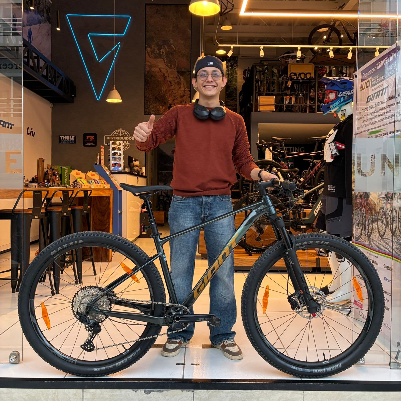 Cliente con su nueva bicicleta de montaña Giant negra en el ventanal de la tienda Giant Juriquilla