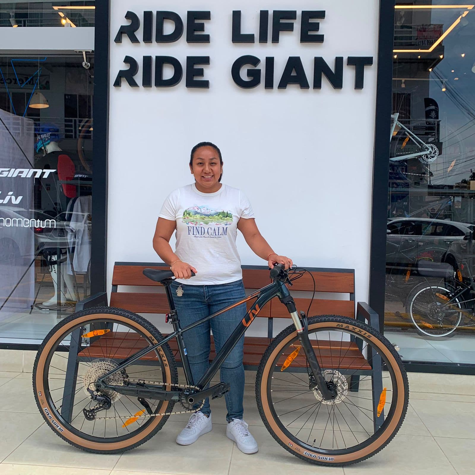 Cliente con su nueva bicicleta gravel Giant gris frente al mural Ride Life Ride Giant