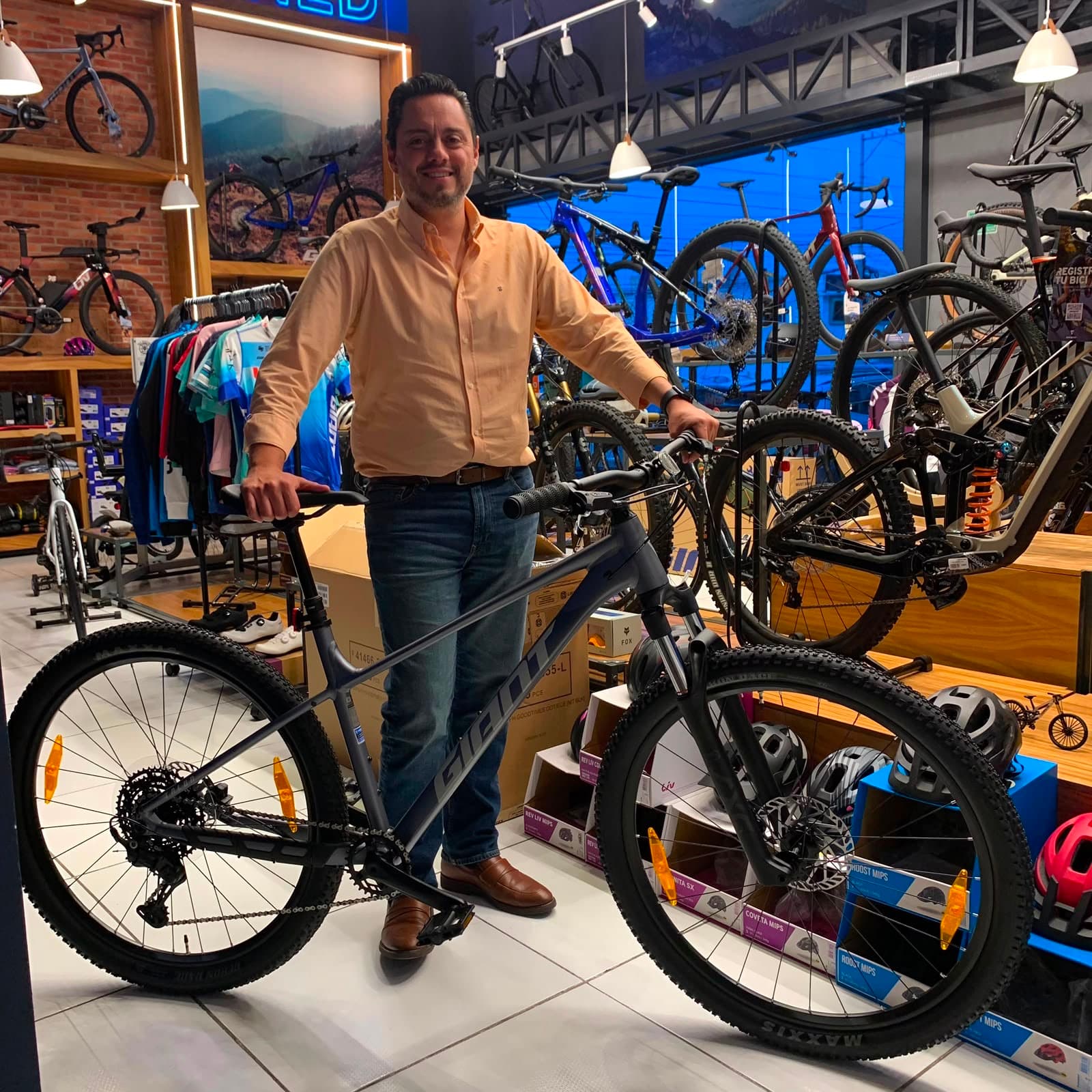 Cliente con su nueva bicicleta de montaña Giant gris en el piso de venta de Giant Juriquilla