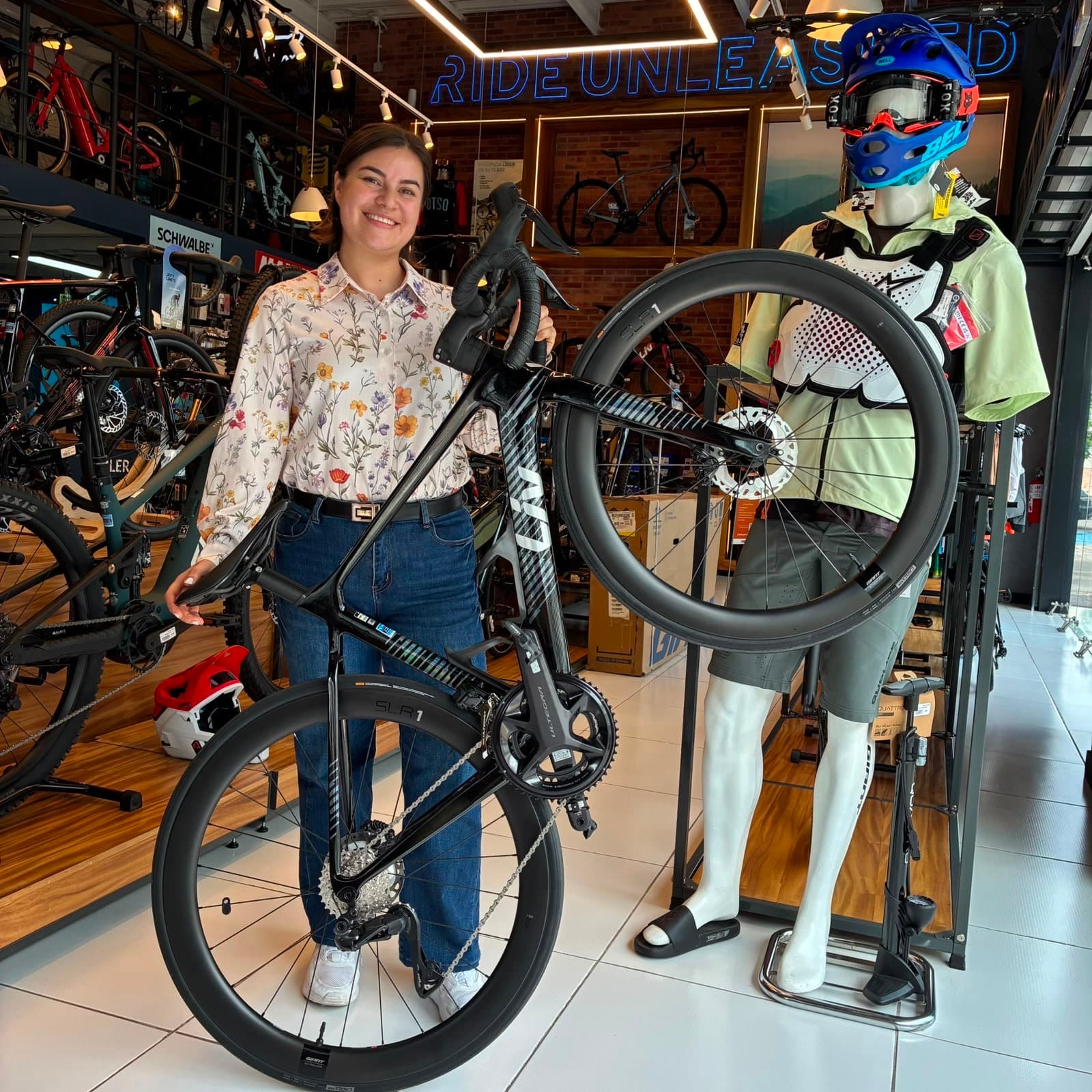 Cliente con su nueva bicicleta de montaña Giant negra junto a la sección de ropa de Giant Juriquilla