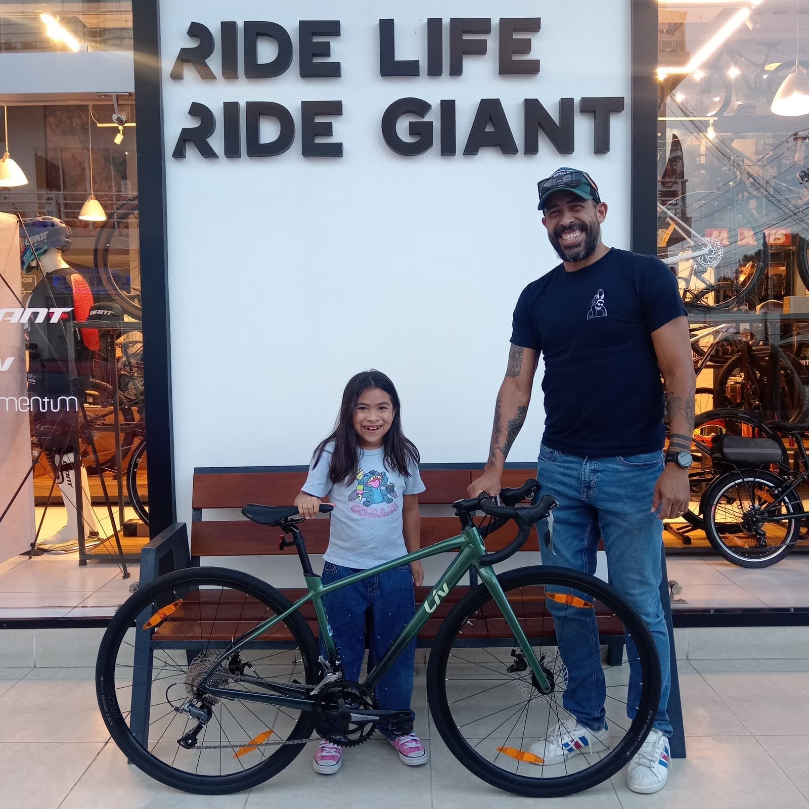 Familia con una nueva bicicleta Giant verde frente al mural Ride Life Ride Giant