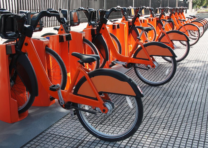 Fila de bicicletas urbanas naranjas en una estación de préstamo