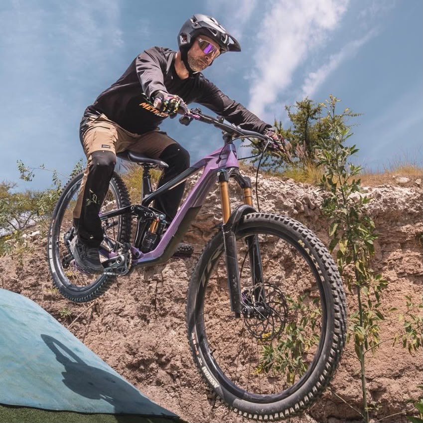 Embajador de Giant Juriquilla en una bicicleta de montaña eléctrica morada bajando un talud de tierra