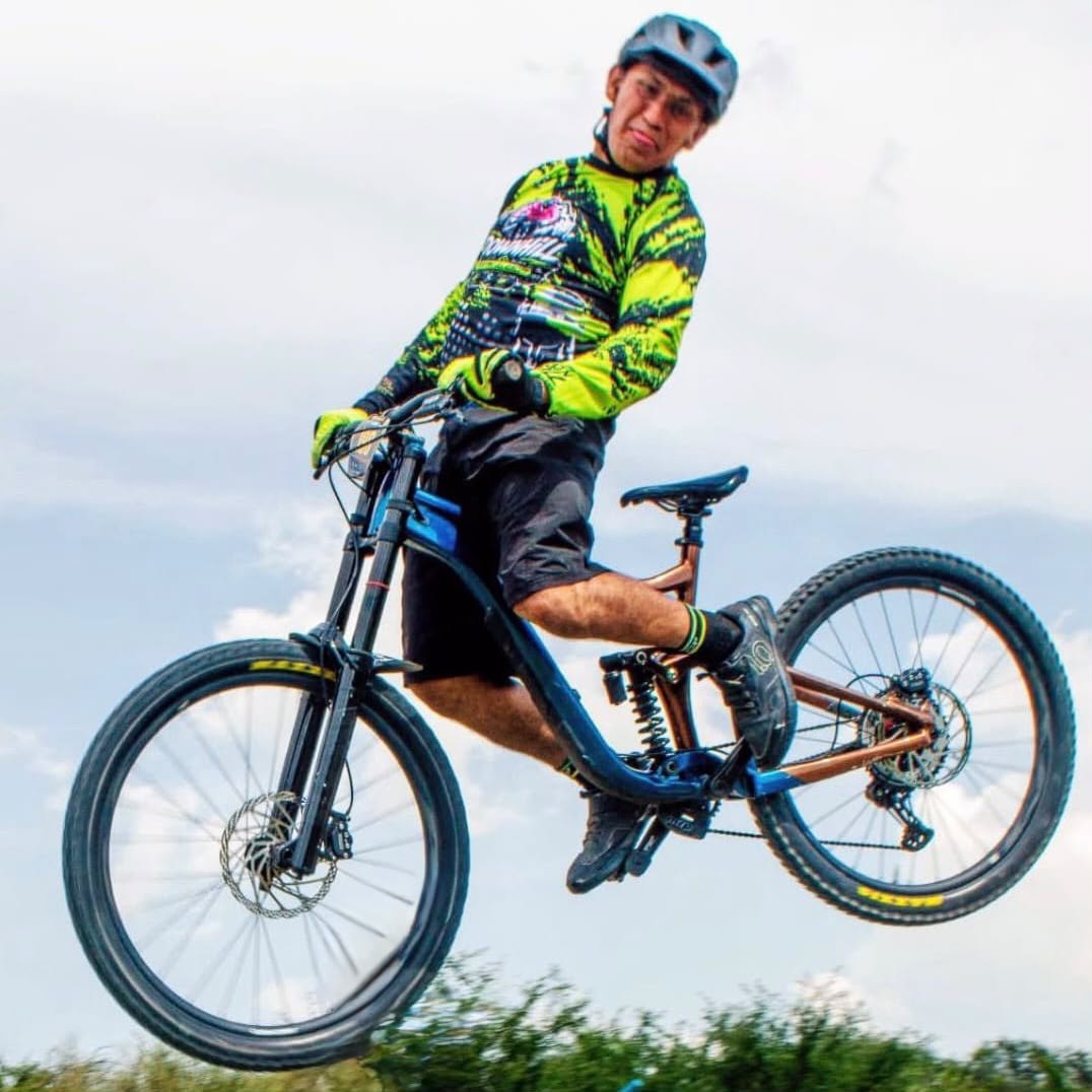 Embajador de Giant Juriquilla en el aire con una bicicleta de descenso y jersey verde fluorescente