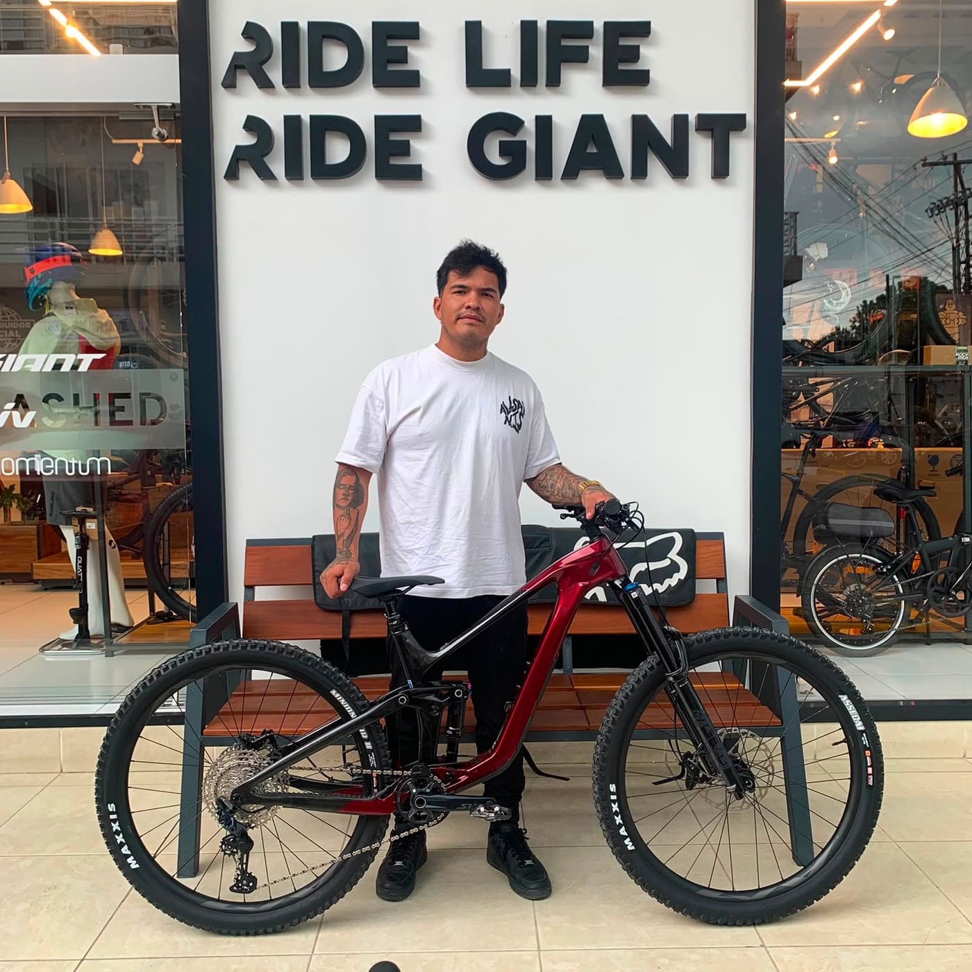 Cliente con su nueva bicicleta de montaña Giant doble suspensión roja frente a la tienda Giant Juriquilla