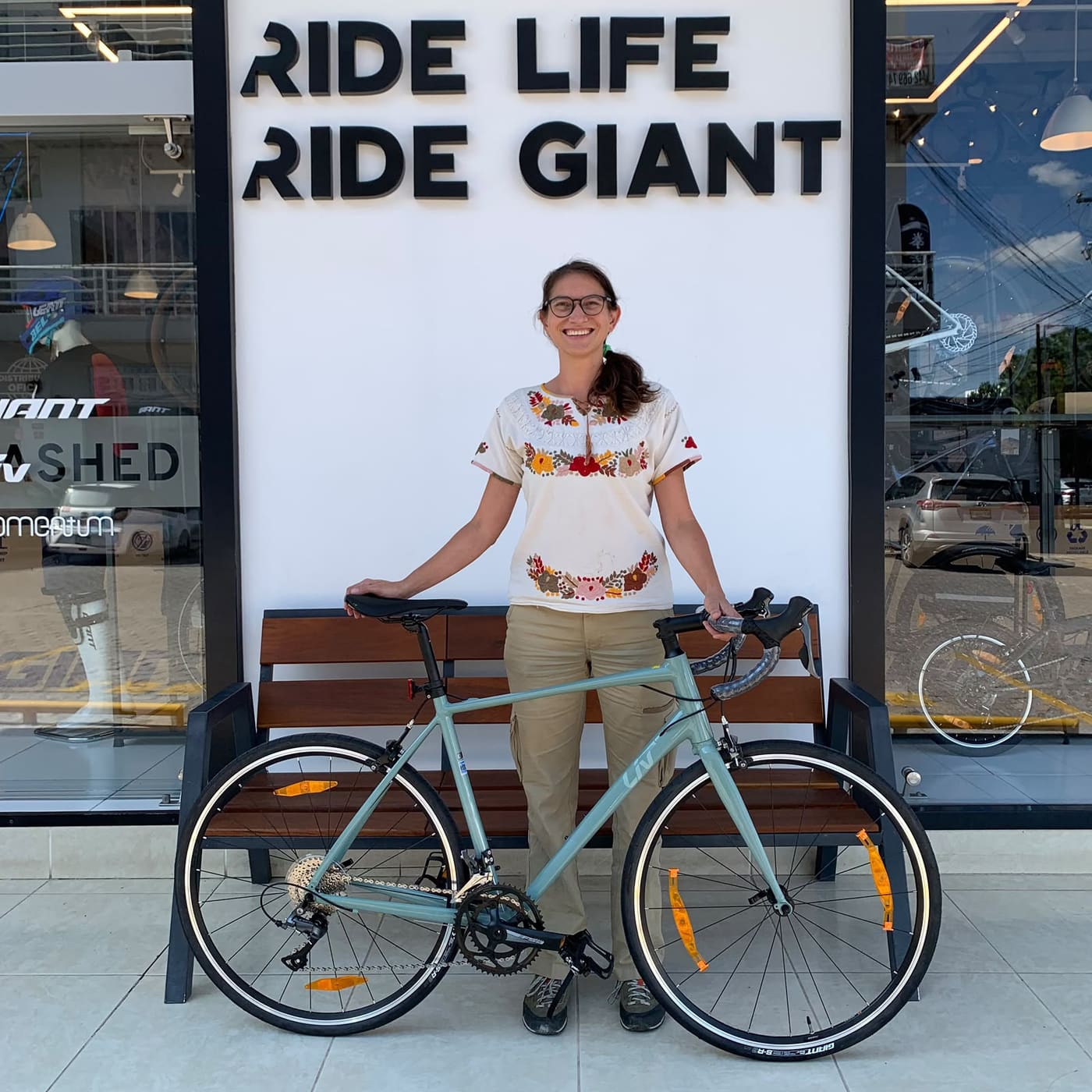 Cliente con su nueva bicicleta urbana Giant verde menta junto a la banca de la fachada