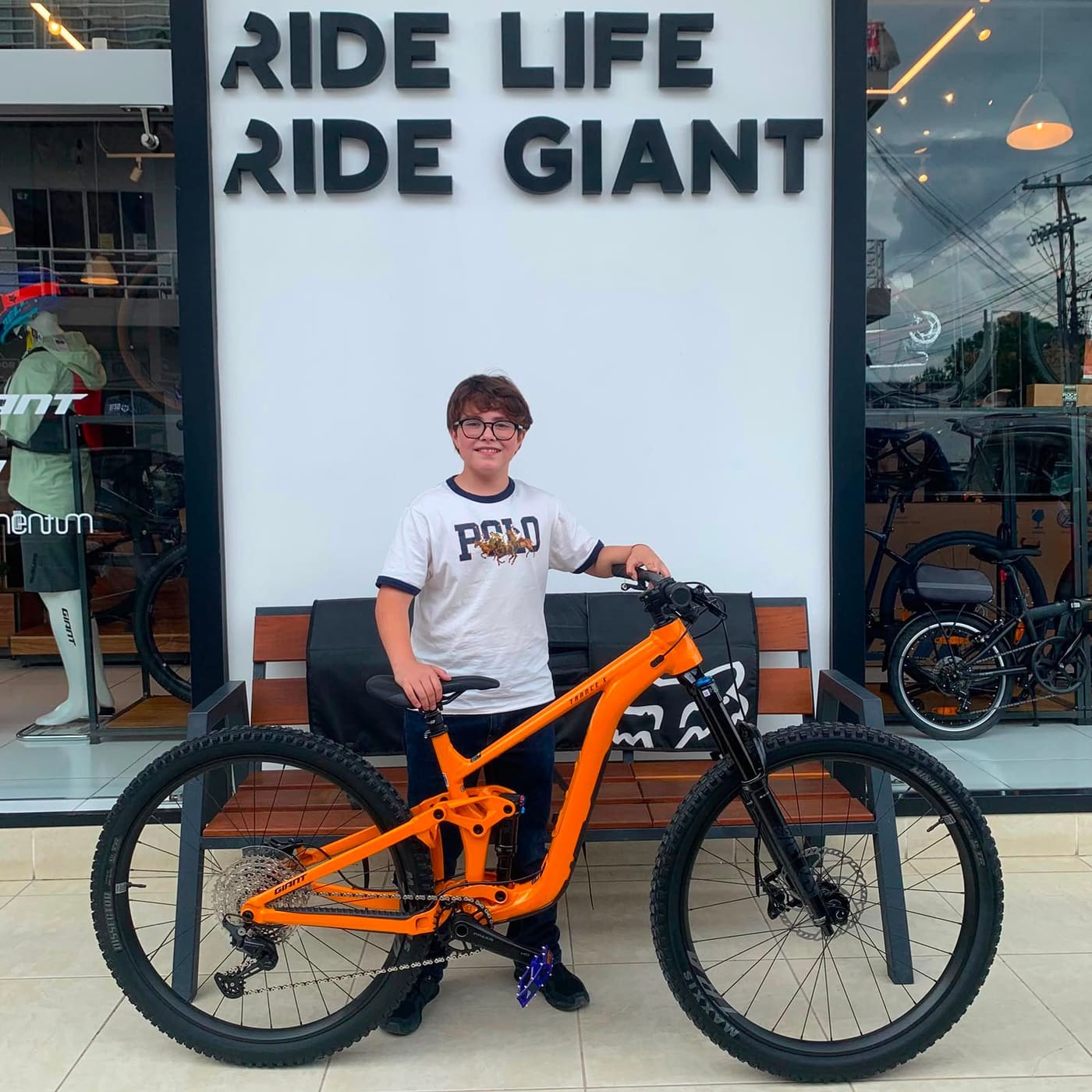Cliente joven con su nueva bicicleta de montaña Giant naranja frente a la tienda Giant Juriquilla