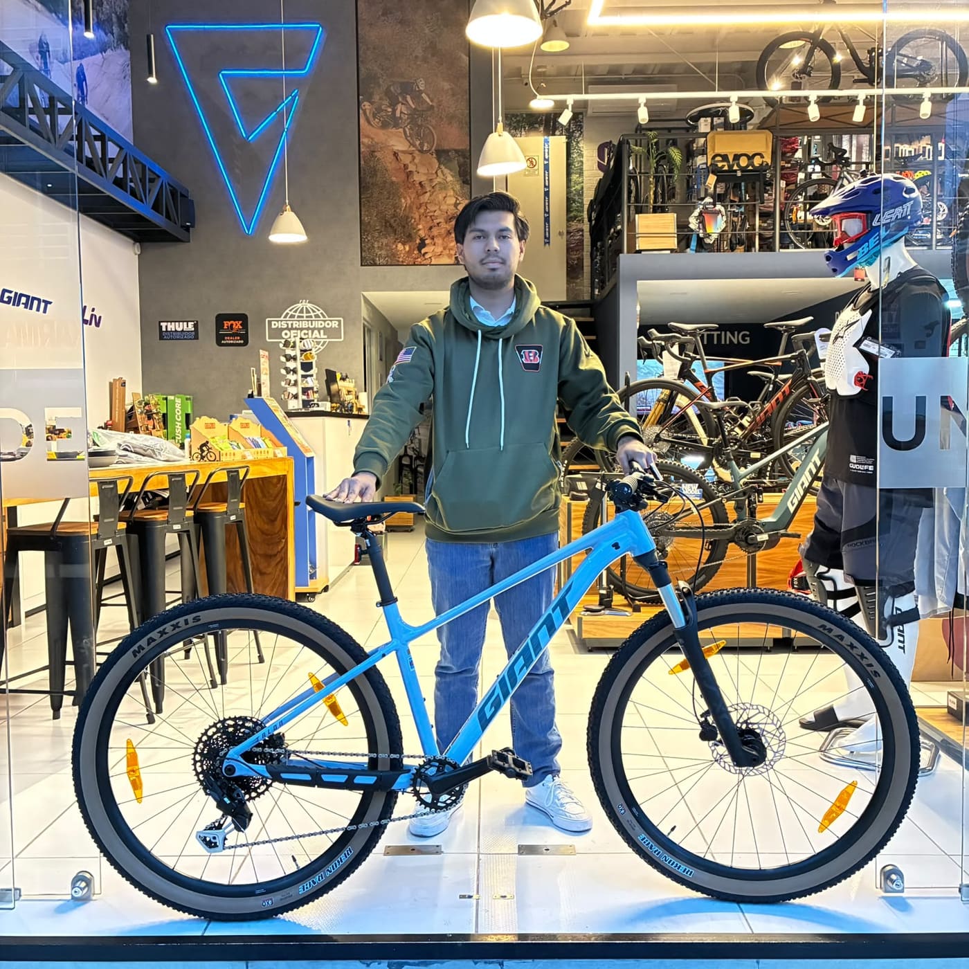 Cliente con su nueva bicicleta de montaña Giant azul en el ventanal de la tienda Giant Juriquilla