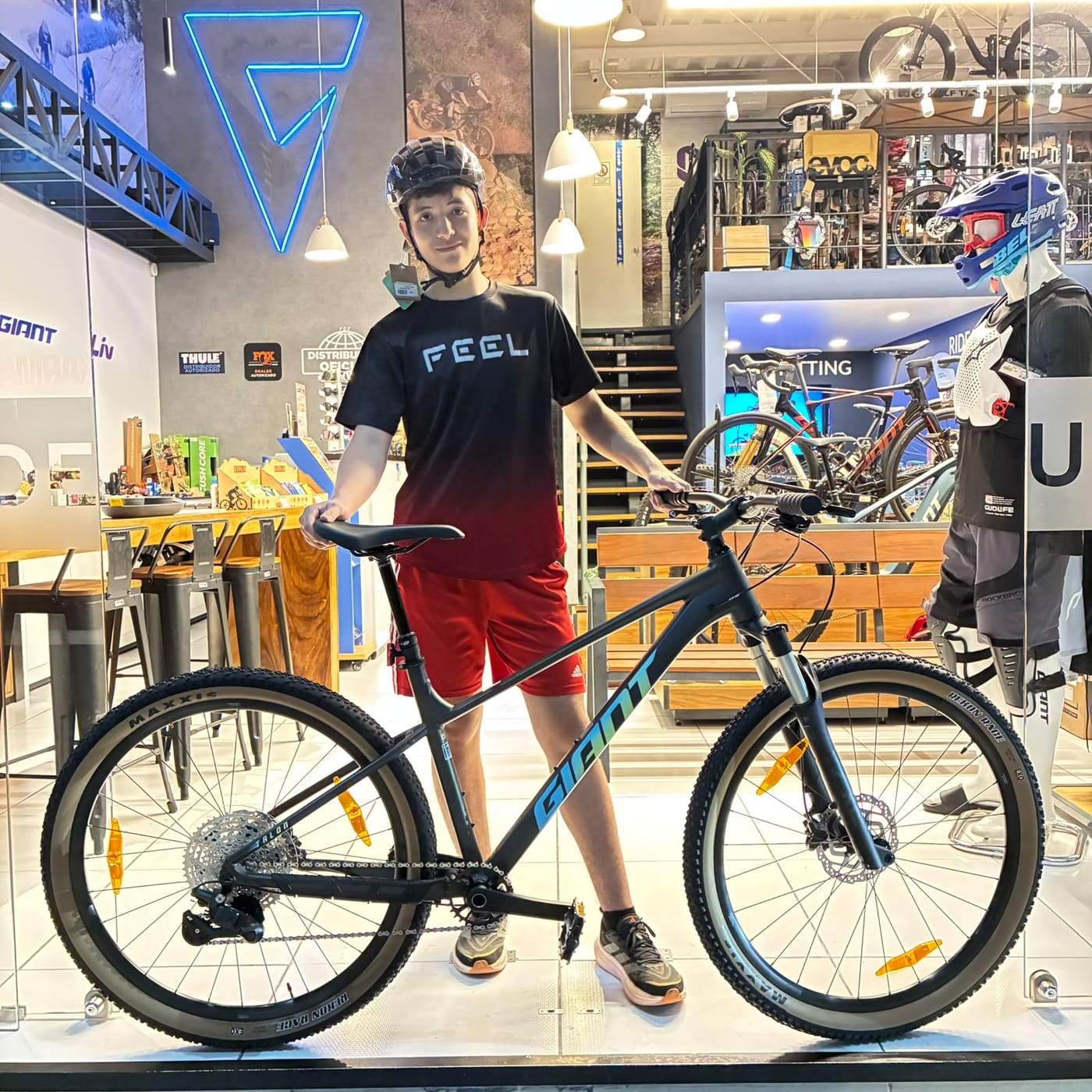 Cliente joven con su nueva bicicleta de montaña Giant gris en el ventanal de la tienda