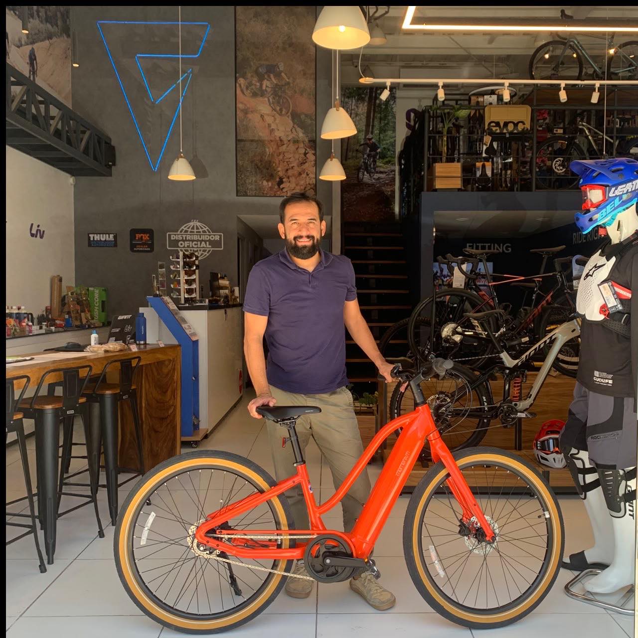 Cliente con su nueva bicicleta urbana Giant naranja de llantas banda café en la tienda