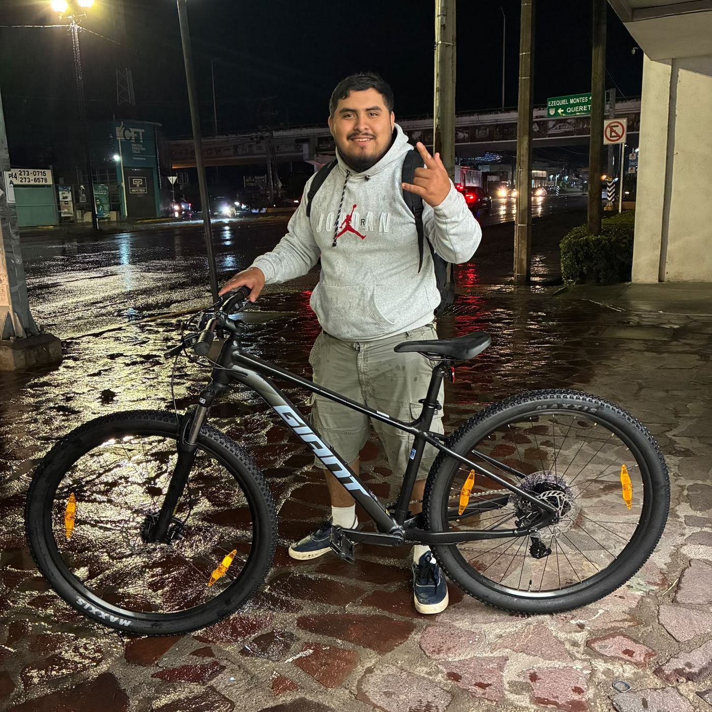 Cliente con su nueva bicicleta de montaña Giant negra, de noche, en la calle