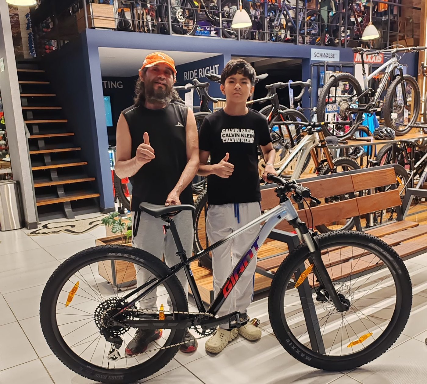 Padre e hijo con su nueva bicicleta de montaña Giant gris y roja en la tienda