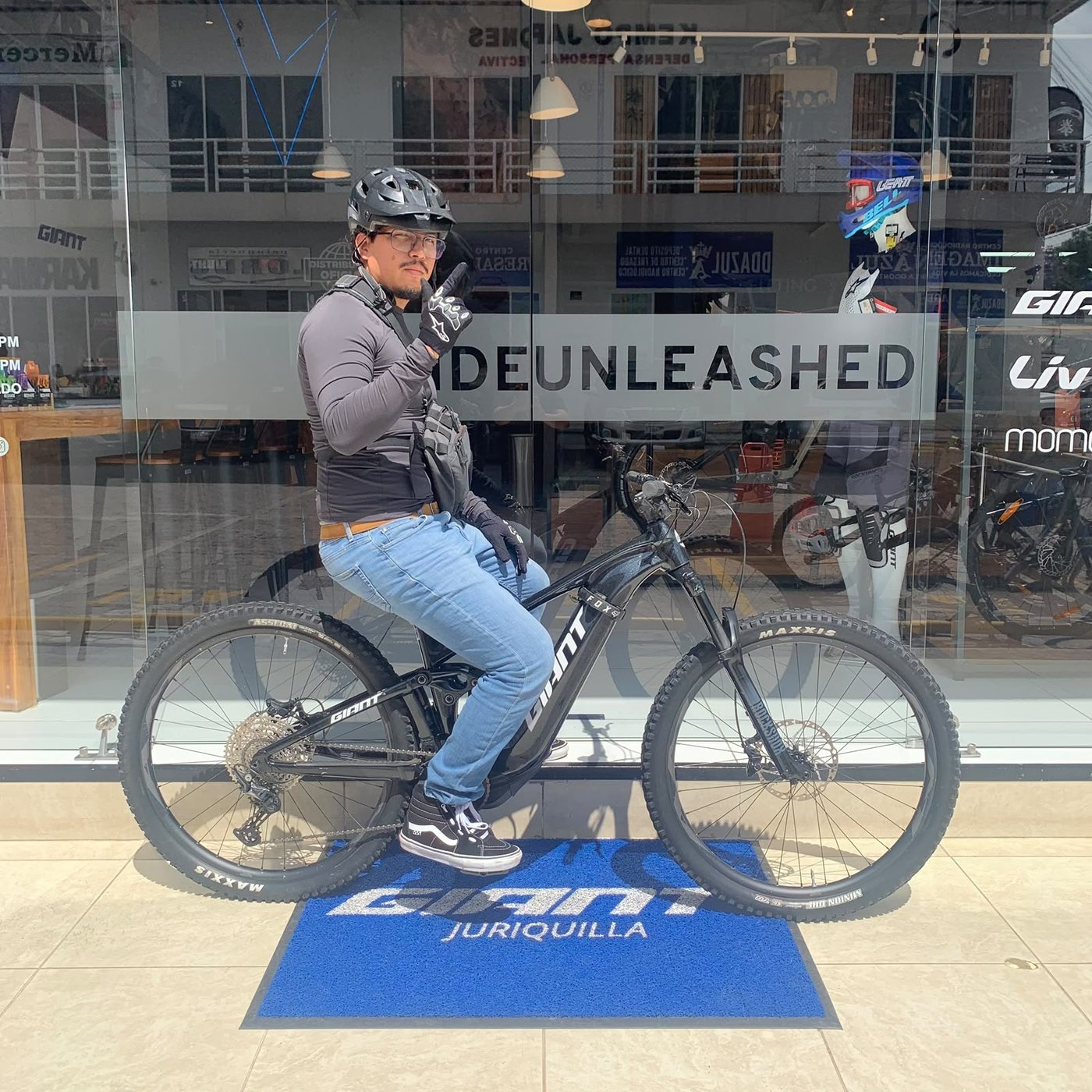 Cliente sentado en su nueva bicicleta de montaña eléctrica Giant negra sobre el tapete de la tienda