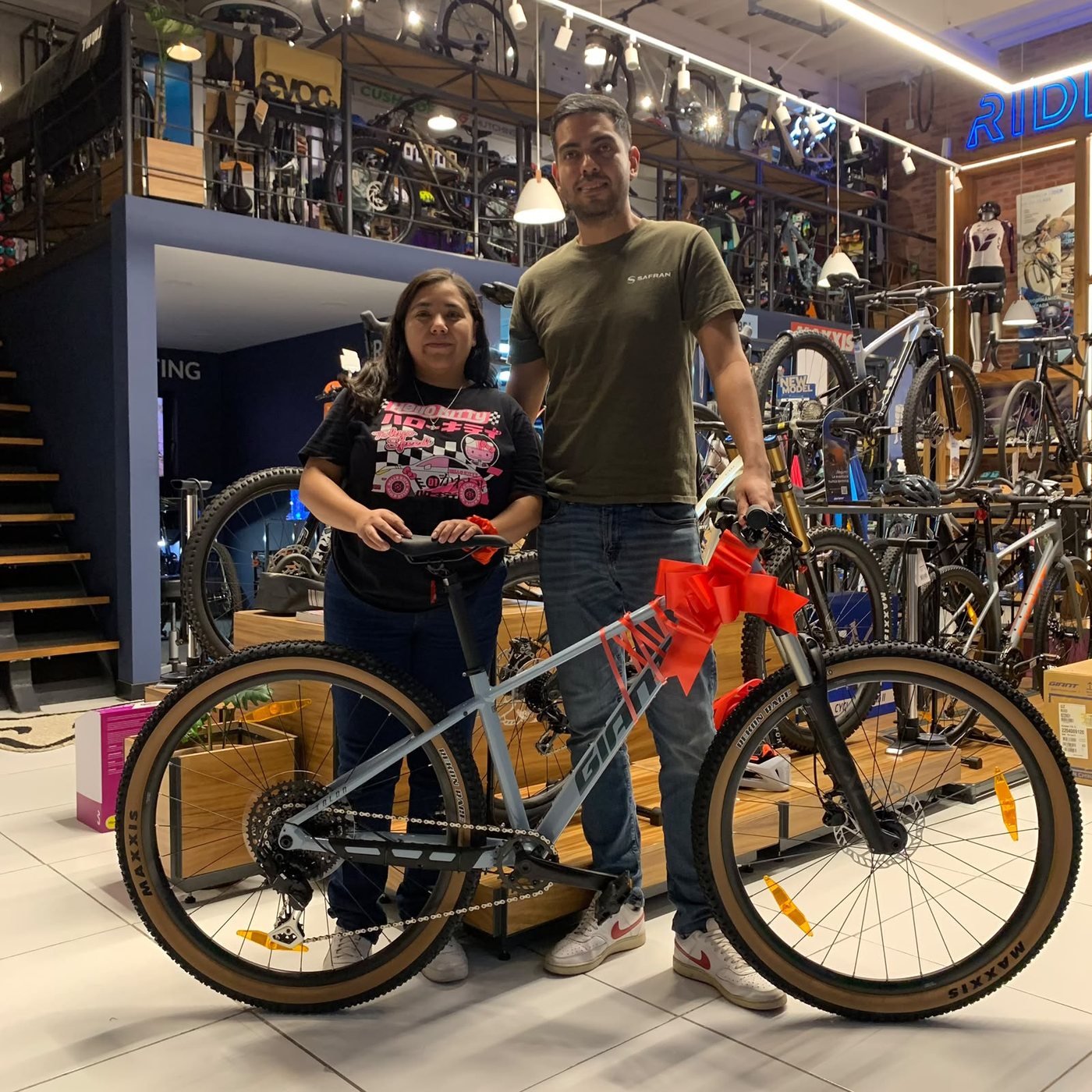 Dos clientes con su nueva bicicleta de montaña Giant gris con un moño rojo en el manillar