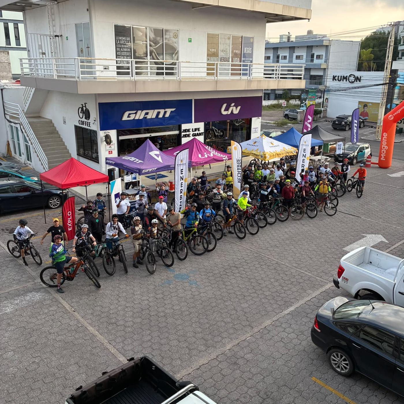 Vista aérea del grupo reunido frente a la tienda, con las carpas Giant y Liv, antes de salir a rodar