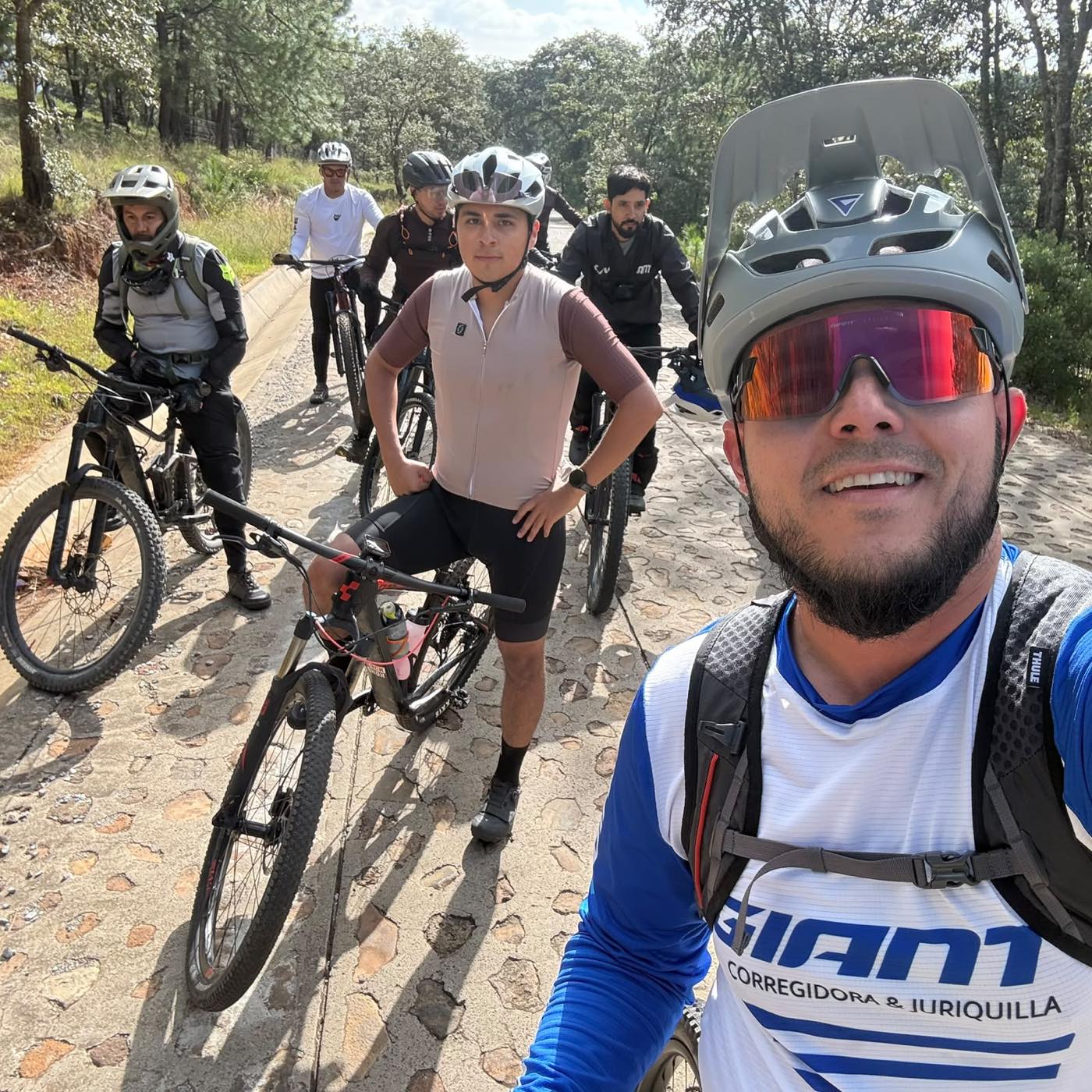Selfie del grupo en un camino empedrado entre pinos durante una rodada de montaña