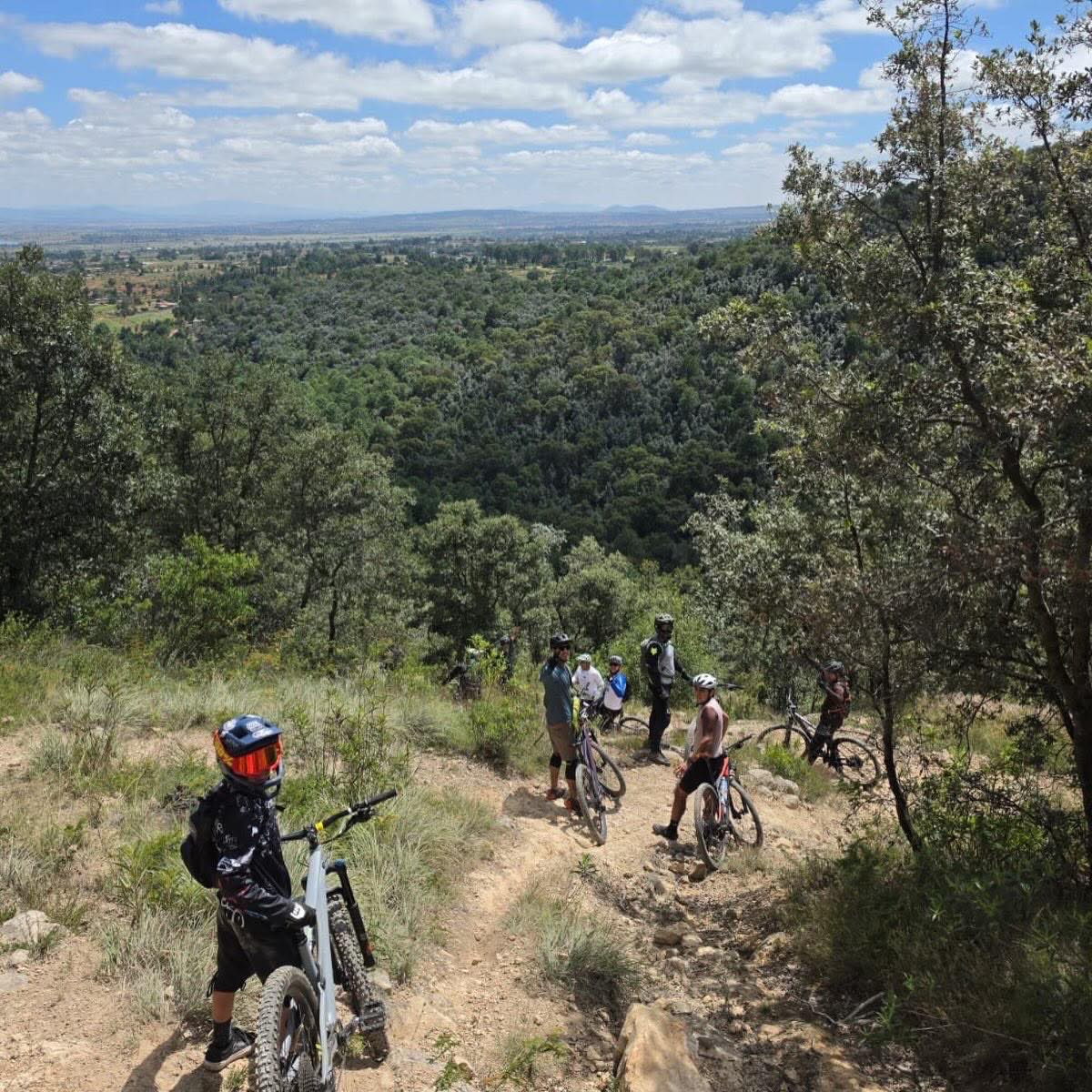 Ciclistas en un sendero angosto del cerro con vista al valle de Querétaro
